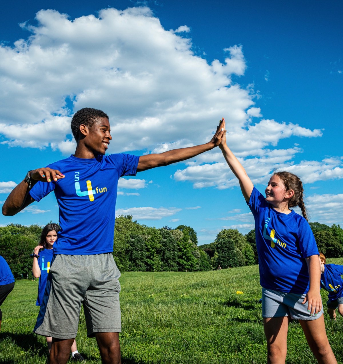 A Run4Fun mentor and a young runner high-fiving in the park