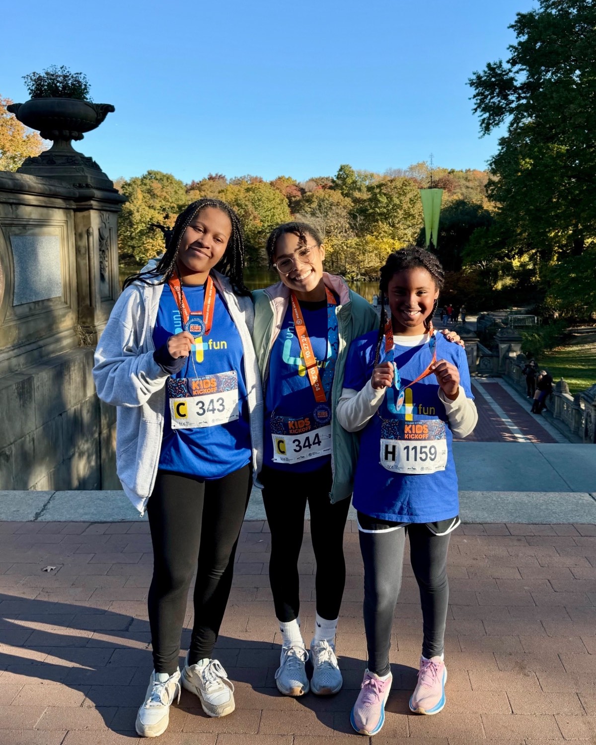 Three Run4Fun runners smiling with their medals after the NYRR Kids Kickoff in Central Park